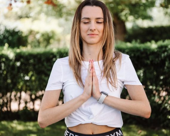 A serene moment of a woman practicing yoga with namaste pose outdoors, embracing mindfulness.