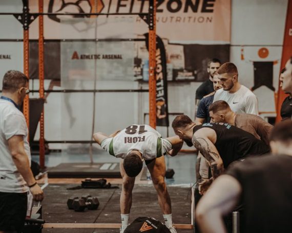 Group of athletes engaging in a competitive CrossFit workout at a gym with emphasis on strength and teamwork.